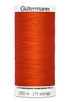 Spool of orange thread with 'Gütermann' branding on a white background