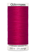 Spool of Gutermann thread in bright pink on a white background