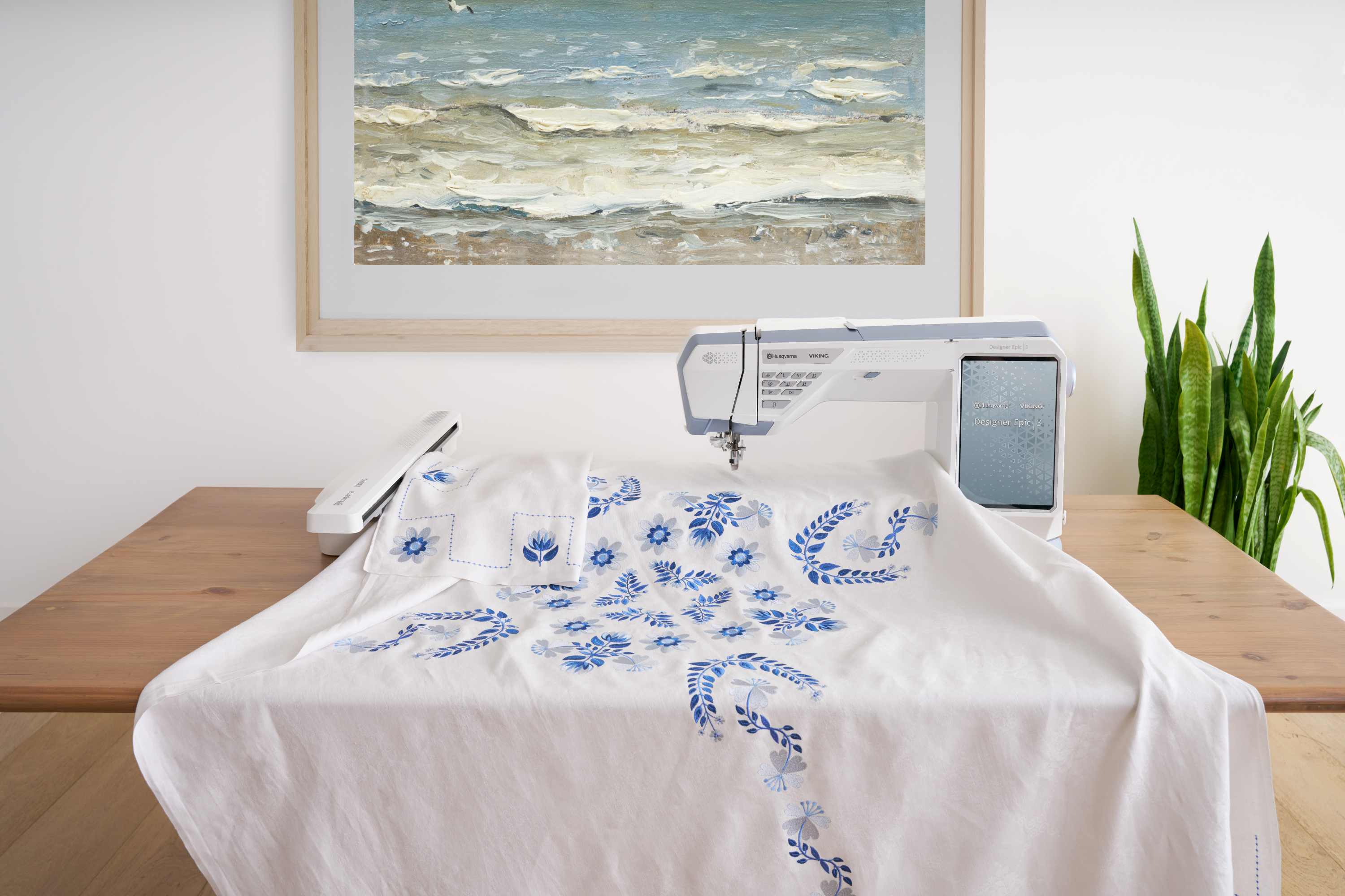 Husqvarna Viking Designer Epic 3 Nordic Frost Sewing and Embroidery Machine Embroidery Example on a Table with Plant and Painting