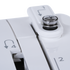 Close-up of a white mechanical device showing adjustment knobs and numbered slots with arrow symbols, photographed on a clean white background.