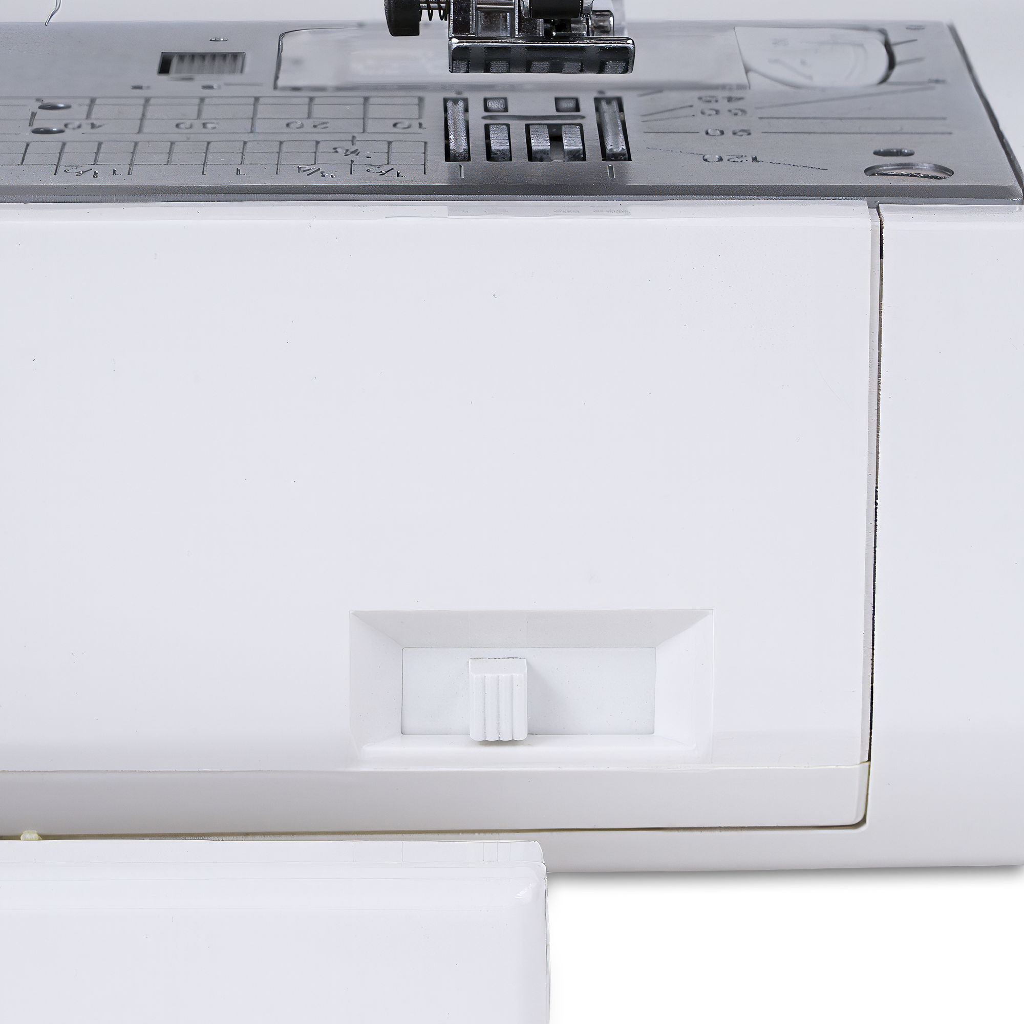 Close-up of a white sewing machine showing the front drawer cover, a small white pull switch, and part of the metallic needleplate with stitch and thread guides.