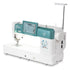 A Janome sewing machine with a white body and teal-green accents, featuring a digital touchscreen display, floral graphic on the side, and an adjustable stand arm, shown on a solid white background.