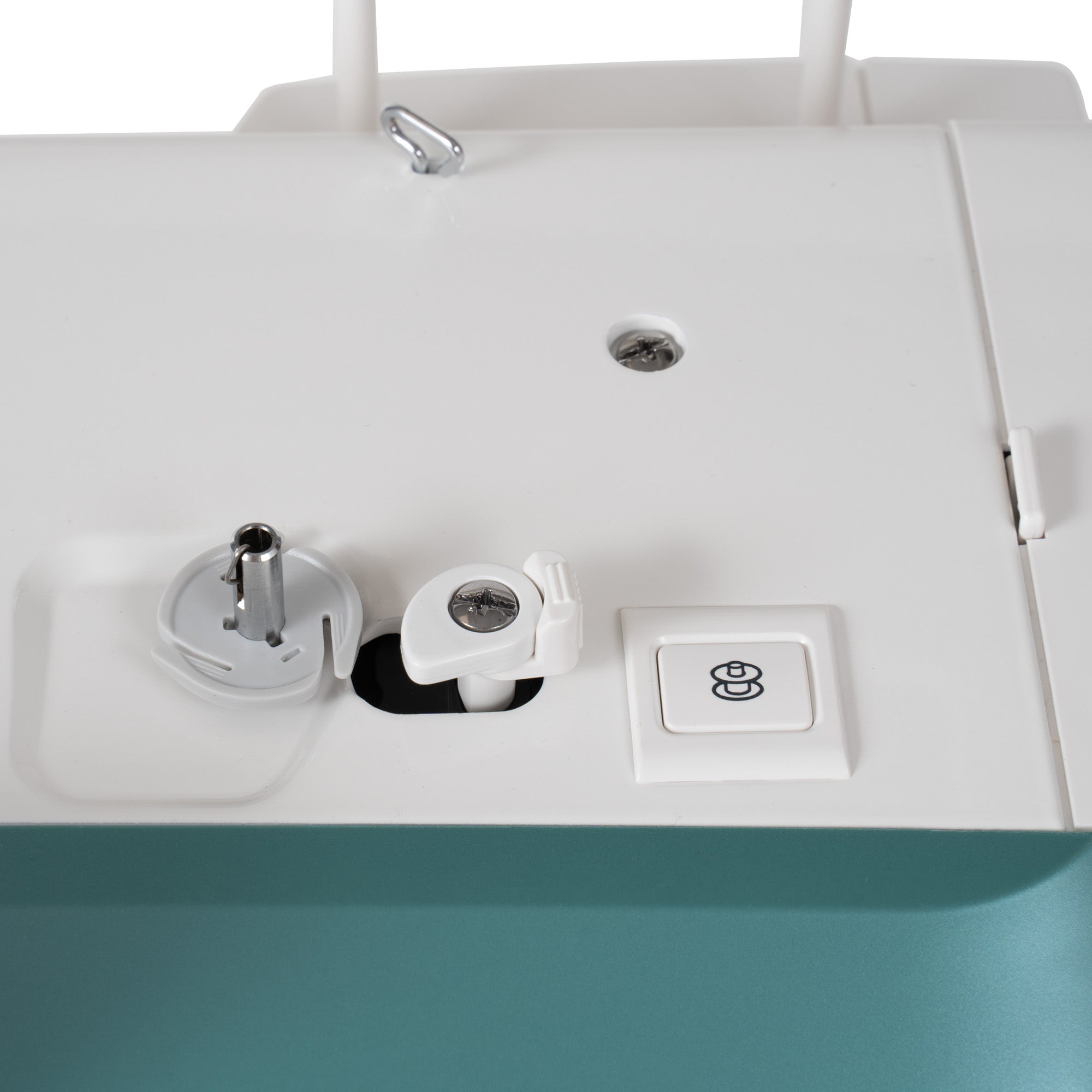 Close-up of the top surface of a white sewing machine, showing a button, metal screw, and a teal lower section.