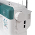 A close-up of a sewing machine showing the side panel with a white body, a teal upper section, a large white dial, power switches, and a floral print on the front.