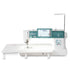 A Janome sewing machine with a long white extended table, a teal digital control panel, and a white body with a floral graphic on the side, shown against a plain white background.