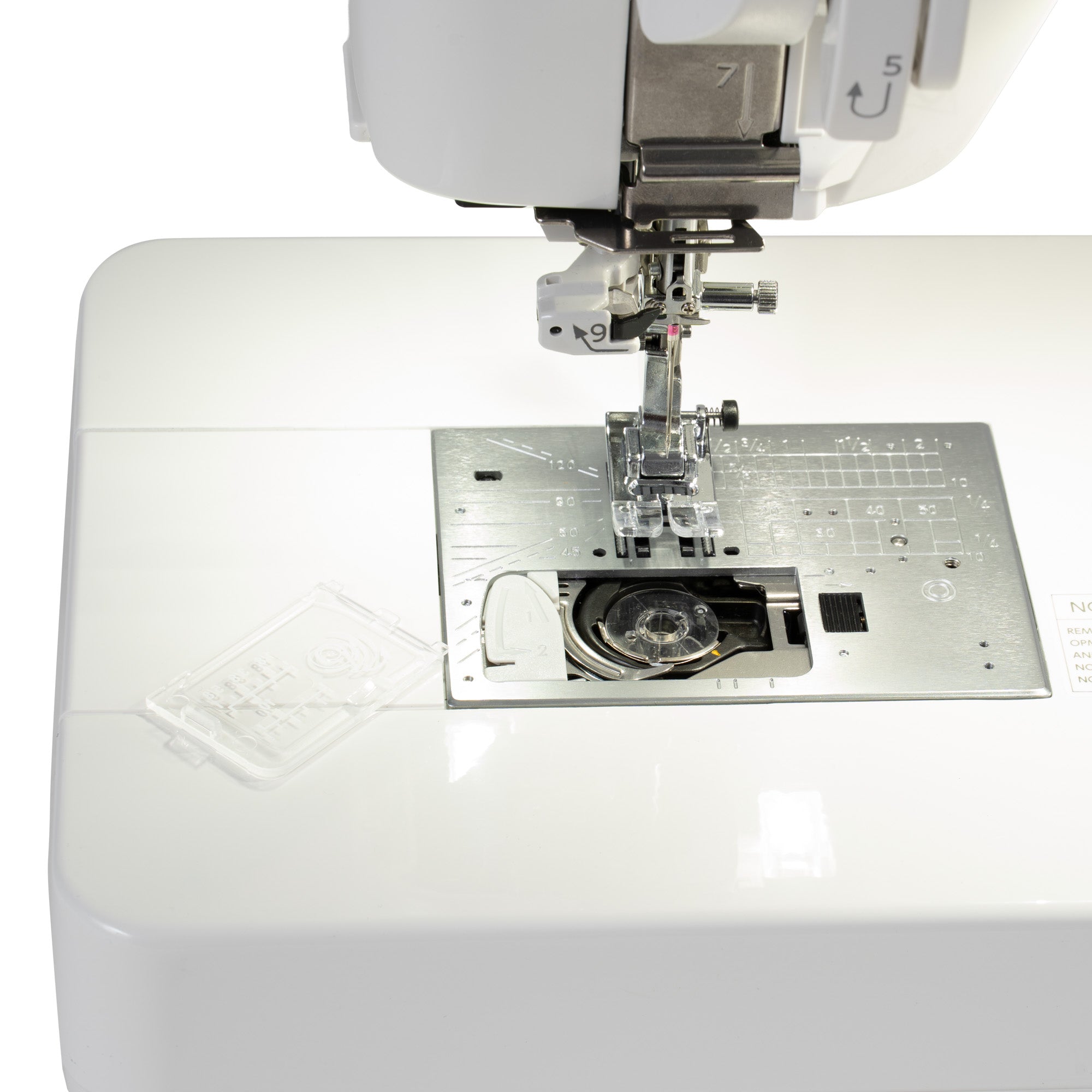 Close-up of a white sewing machine showing the needle area, presser foot, metal needle plate, and a small clear plastic cover on a white surface.