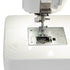 Close-up of a white sewing machine showing the needle area, presser foot, metal needle plate, and a small clear plastic cover on a white surface.