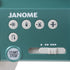 Close-up of a teal Janome sewing machine control panel with white buttons, including a start-stop button, directional arrows, and a speed slider.