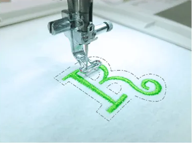 Embroidery machine stitching a green letter 'R' on fabric