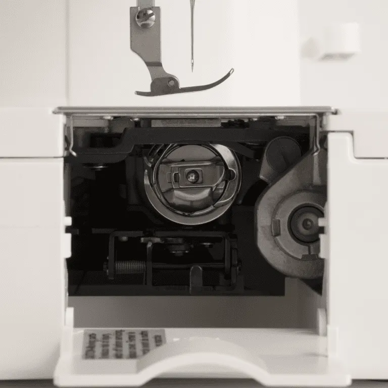 Close-up of a white sewing machine showing the open front cover, internal mechanism, and a metal press foot above the needle area.