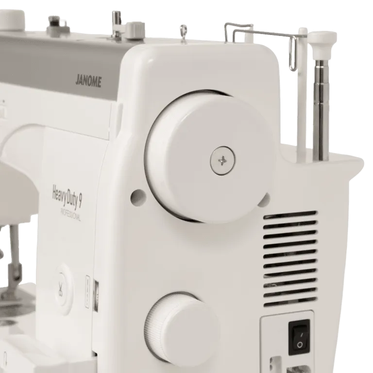 Close-up of a Janome Heavy Duty 9 sewing machine body in white, showing the large front dial, side vent, power switch, and part of the needle clamp area on a clean white background.