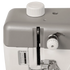 Close-up of a sewing machine showing the top cover, white cap, tension dial, and metal press foot on a white and gray machine body.