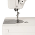 Close-up of a white sewing machine showing the needle area, presser foot, metal plate, and a small round metal dial on the side, photographed on a clean white background.