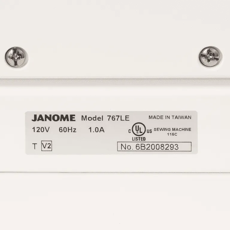 Close-up of a JANOME sewing machine nameplate showing model 767LE, 120V 60Hz 1.0A, UL listed, and made in Taiwan on a white machine surface.