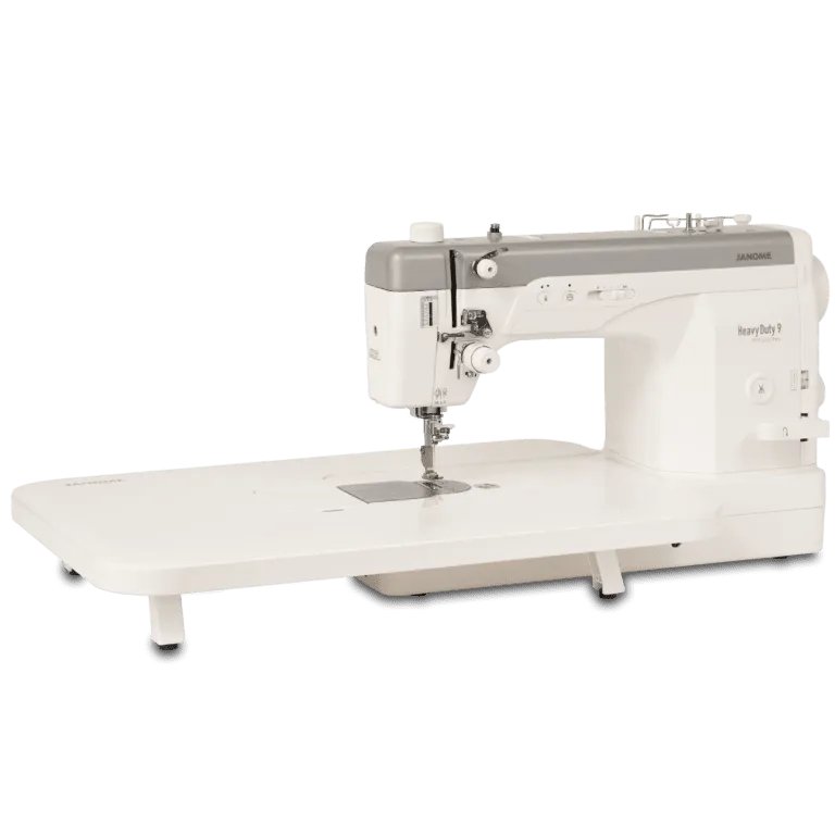 A heavy-duty sewing machine with a long flat table base, shown from a three-quarter angle on a solid white background. The machine features a white body with a gray top cover and silver metal components.