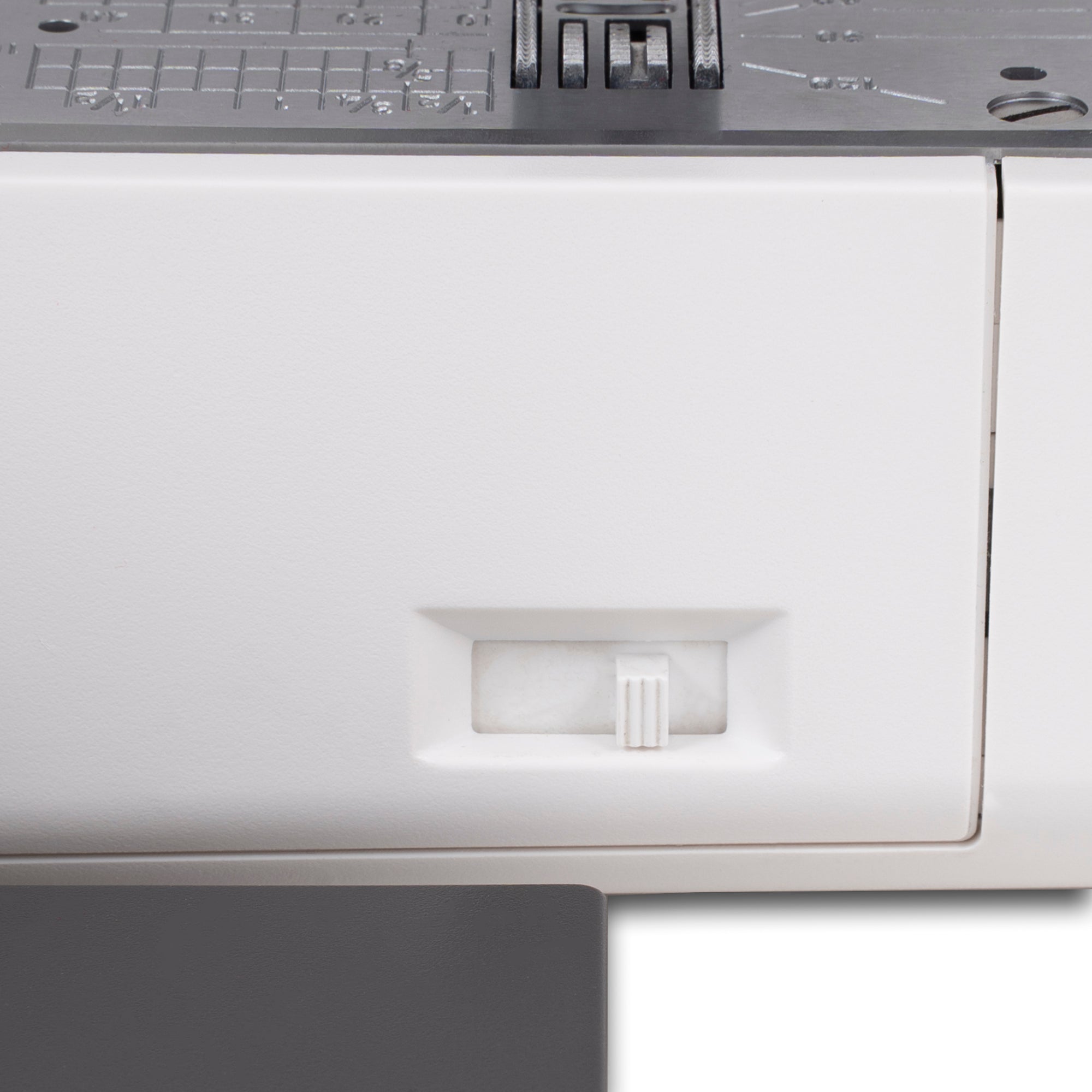 Close-up of a white sewing machine panel with a small recessed switch and a dark gray top control section.