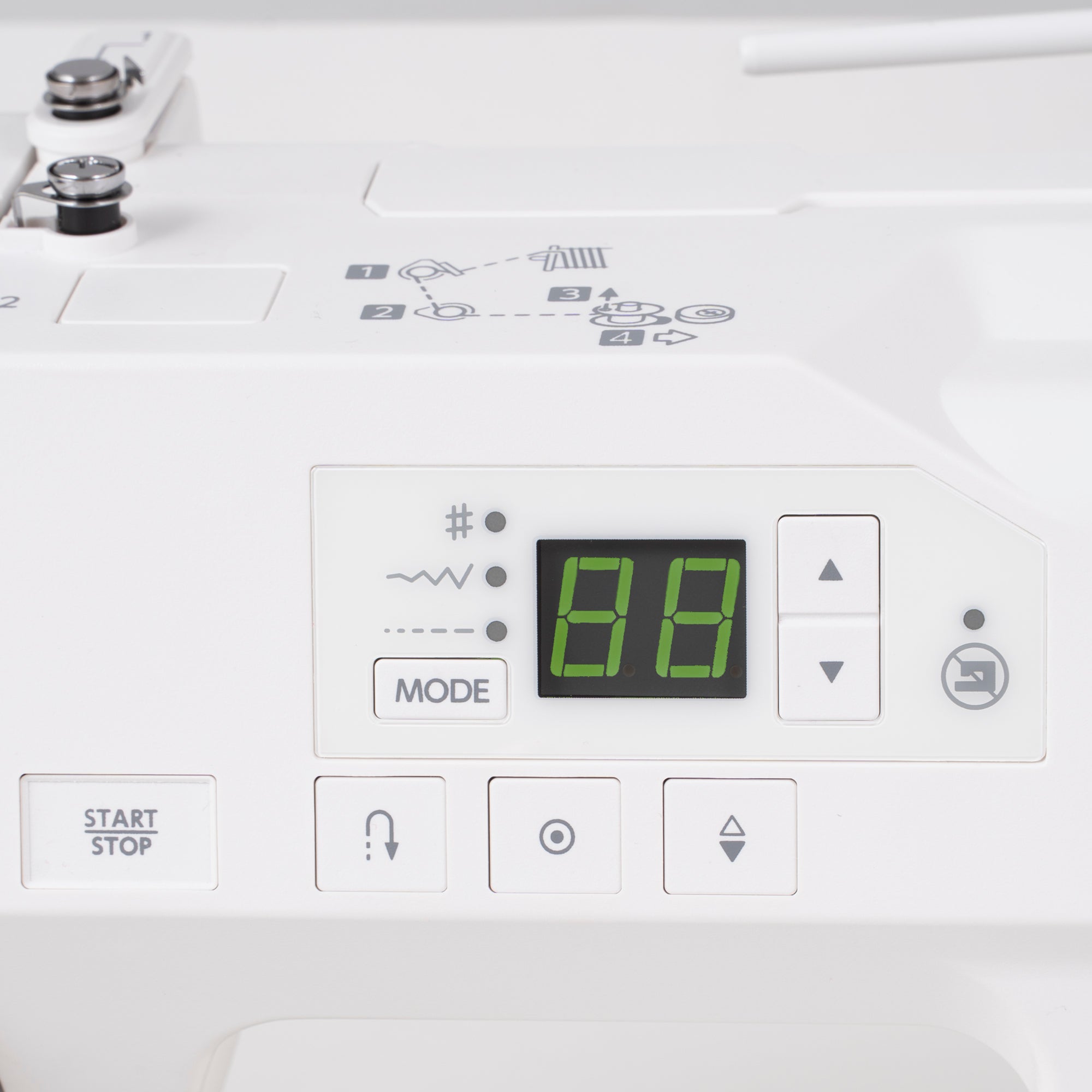 Close-up of a white sewing machine control panel with a green digital display showing '88', mode and start/stop buttons, and stitch pattern icons printed above.