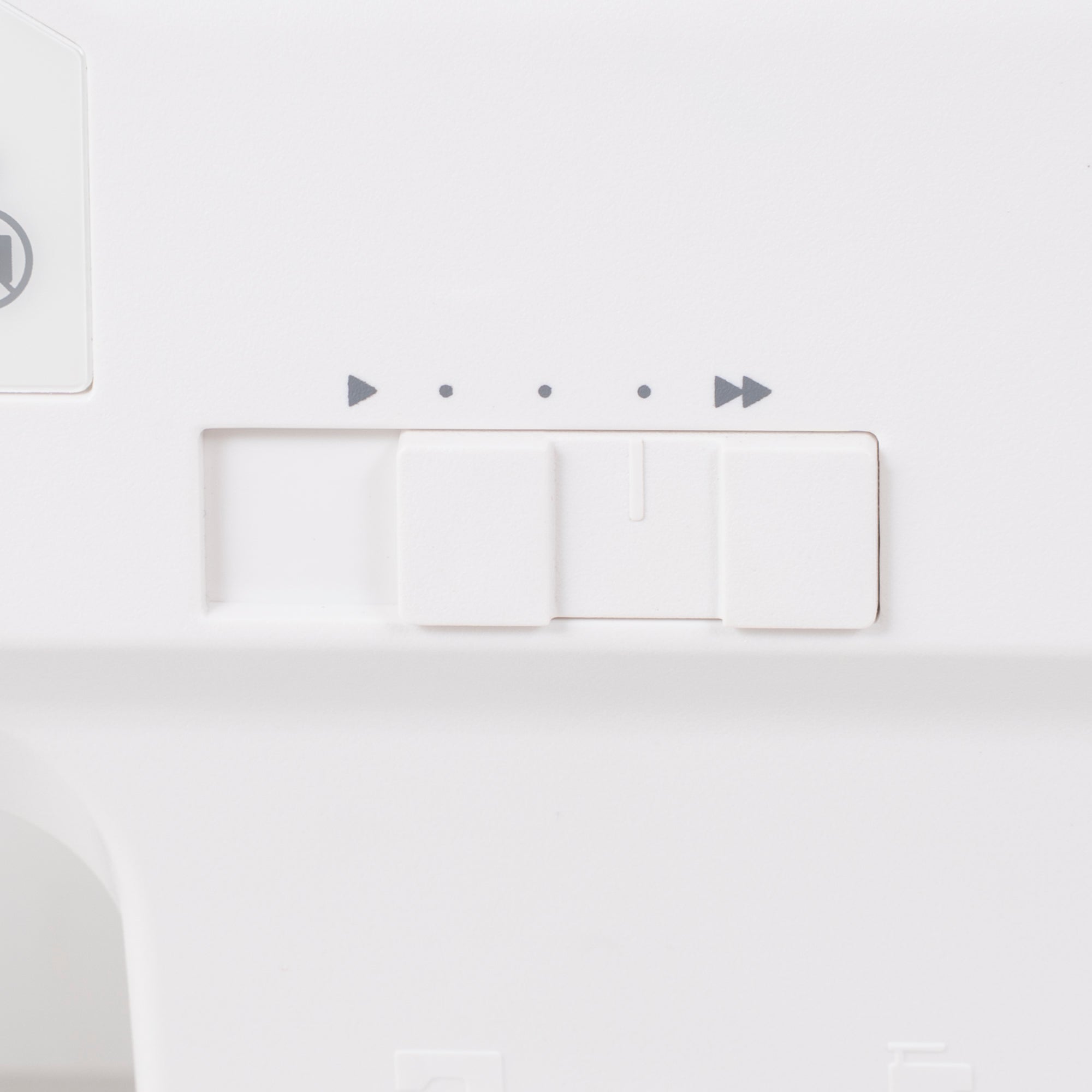 Close-up of a white electronic control panel with three rectangular buttons and small gray playback-style icons above them.