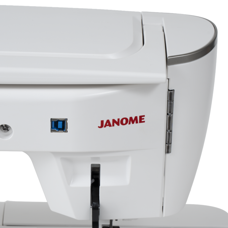 Close-up of a white Janome sewing machine showing the side panel with a red JANOME logo, a blue USB-A port, and a black lever, on a white background.