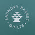 A square teal packaging card or box featuring a white circular logo that reads 'LAUNDRY BASKET QUILTS' around a central geometric basket icon.