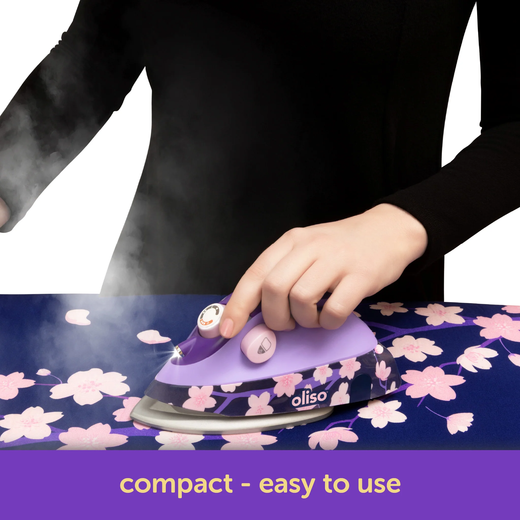 Person ironing fabric with a purple Oliso iron on a floral patterned surface.