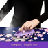 Person ironing fabric with a purple Oliso iron on a floral patterned surface.
