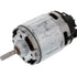 A used cylindrical electric motor with a silver metal body, a protruding metal shaft, and a black plastic housing on one end, shown against a plain white background.