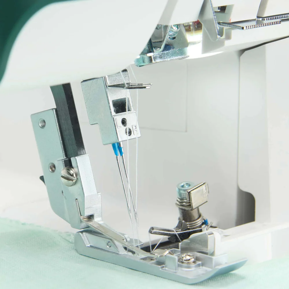 Close-up of a sewing machine needle and presser foot on a light green fabric background