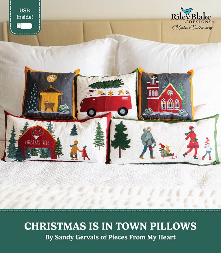 Six Christmas-themed decorative throw pillows arranged on a bed with white pillows and a beige headboard. The pillows feature festive winter scenes including a red truck, church, Christmas trees, and people outdoors.