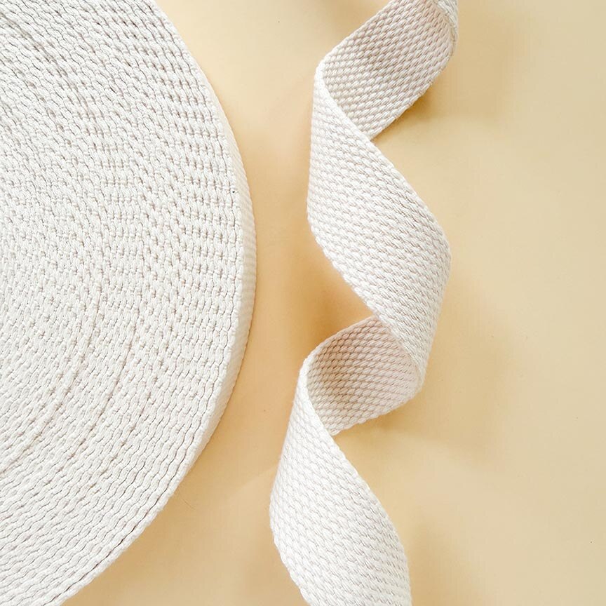 Close-up of a roll of white woven ribbon on a light beige background