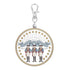 Circular keychain with three figures and a banner on a white background