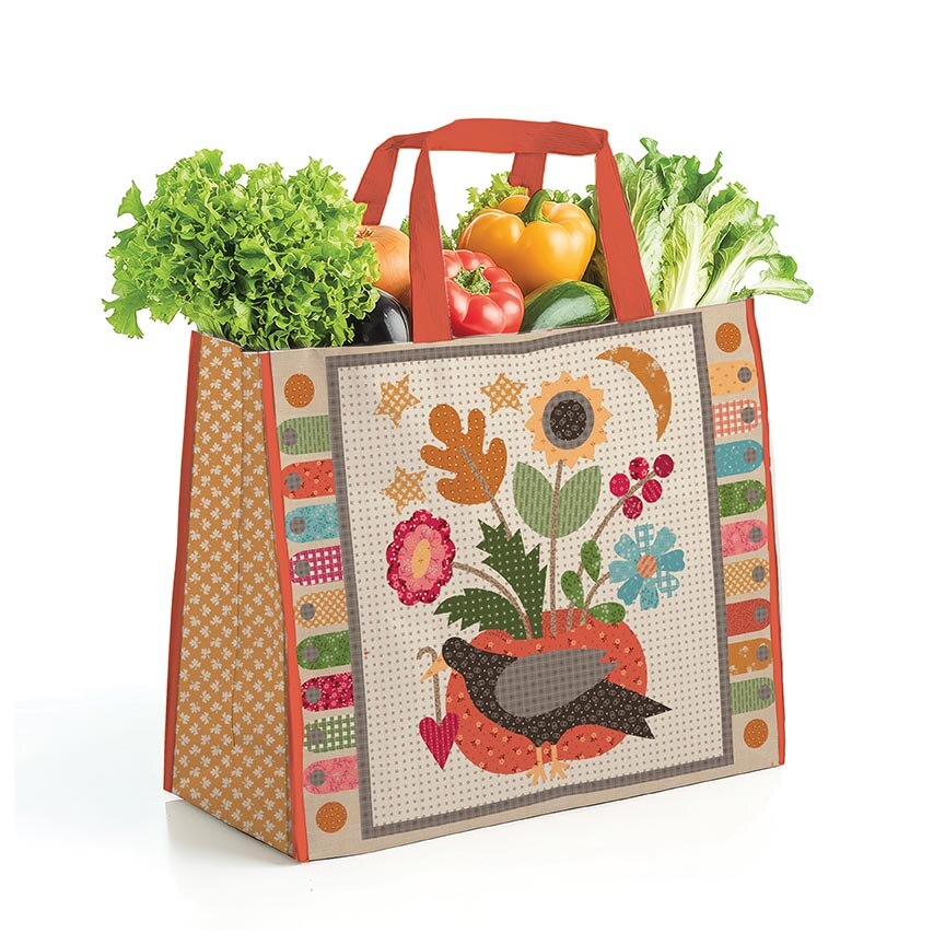 Reusable shopping bag with floral and bird design filled with groceries on a white background