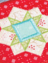 A close-up of a colorful quilted fabric patch featuring a geometric starburst design with a light blue center, green embroidered sections, and cream panels on a red patterned background.
