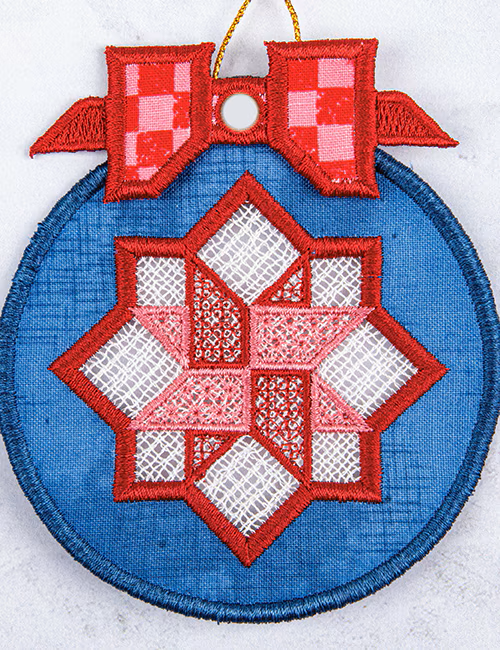 A circular embroidered ornament featuring a blue fabric background with a central red and white geometric star design, topped with a red checkered bow and a gold hanging loop.