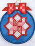 A circular embroidered ornament featuring a blue fabric background with a central red and white geometric star design, topped with a red checkered bow and a gold hanging loop.