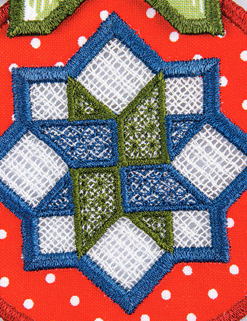 Close-up of a colorful embroidered geometric patch featuring a blue and green star-like pattern over white mesh sections on a red polka-dot fabric background.