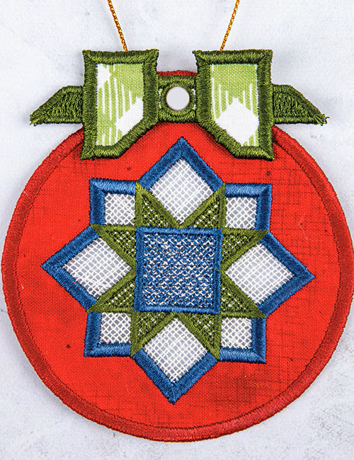 A circular embroidered ornament with a red base, a blue and green geometric star design, and a green bow at the top, shown against a light textured background.