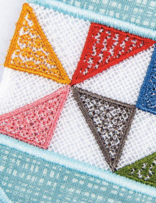 Close-up of a colorful embroidered textile pattern featuring six triangular sections in orange, red, pink, brown, blue, and green on a white mesh background with a light blue stitched border.