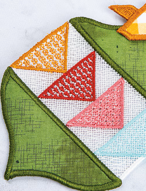 A close-up of a colorful embroidered patch featuring geometric triangles in green, orange, red, pink, and light blue on a white mesh background.