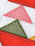 Close-up of a textile or rug featuring a geometric pattern with red borders, a pink triangle, a green triangle, and a white mesh-like center.