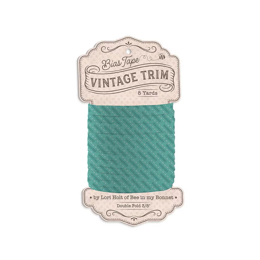 A spool of Bias Tape Vintage Trim in a teal green color, featuring a decorative cream-colored paper label that reads 'Bias Tape Vintage Trim 8 Yards' and 'by Lori Holt of Bee in my Bonnet'.