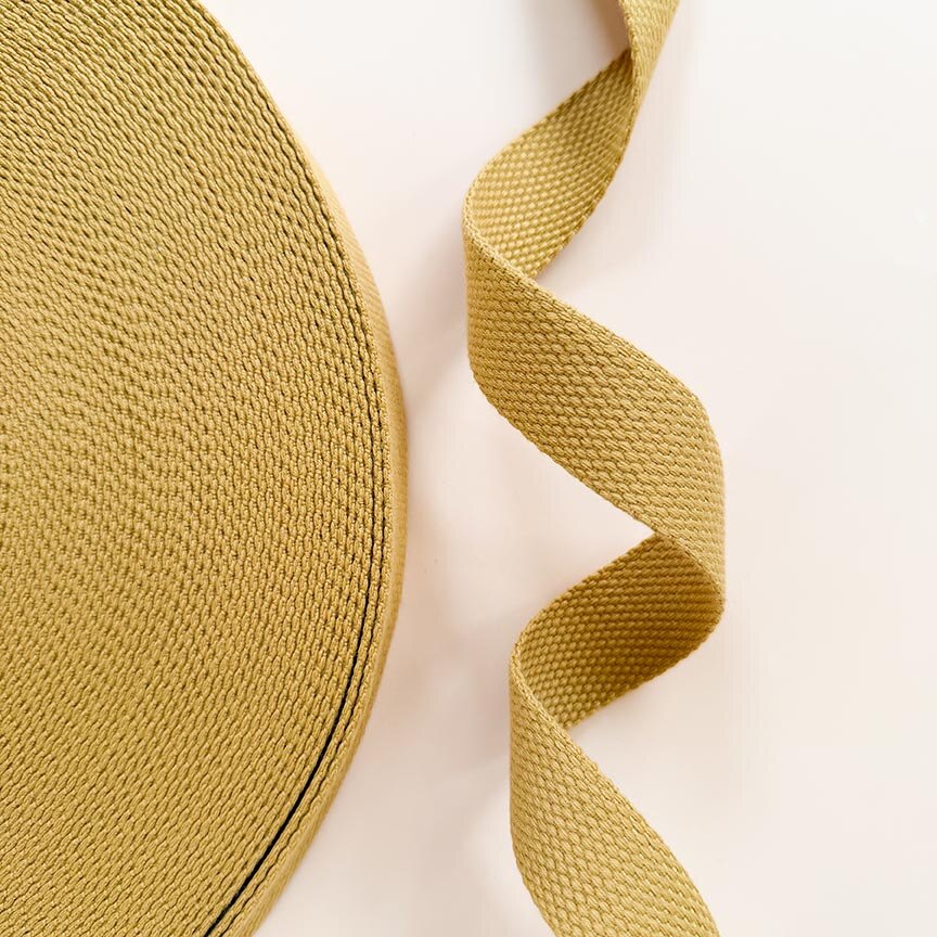Close-up of a roll of yellow woven ribbon on a light beige background