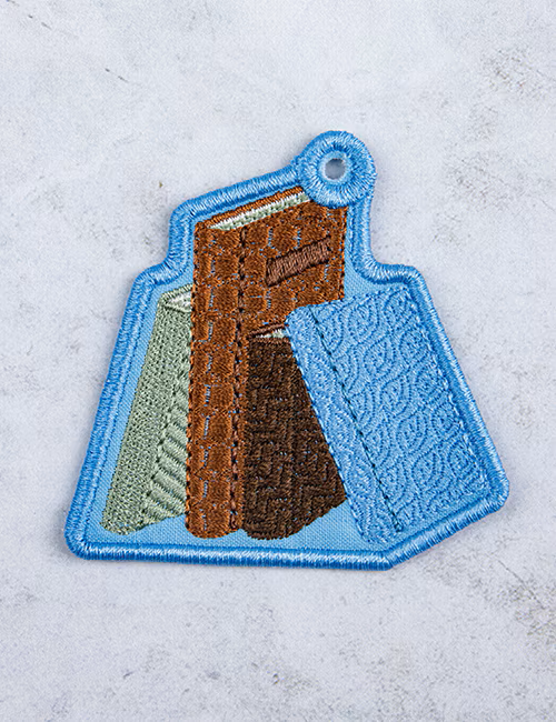 Embroidered patch of a book on a blue background