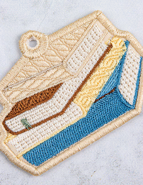 Embroidered patch of books on a textured surface