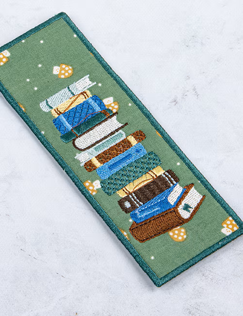 Embroidered patch of stacked books on a green background