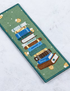 Embroidered patch of stacked books on a green background