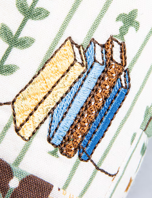 Embroidered design of a book with a yellow cover and blue spine on a green background.