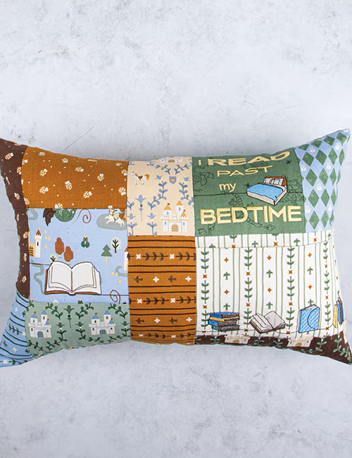 Decorative pillow with book-themed patterns on a white background