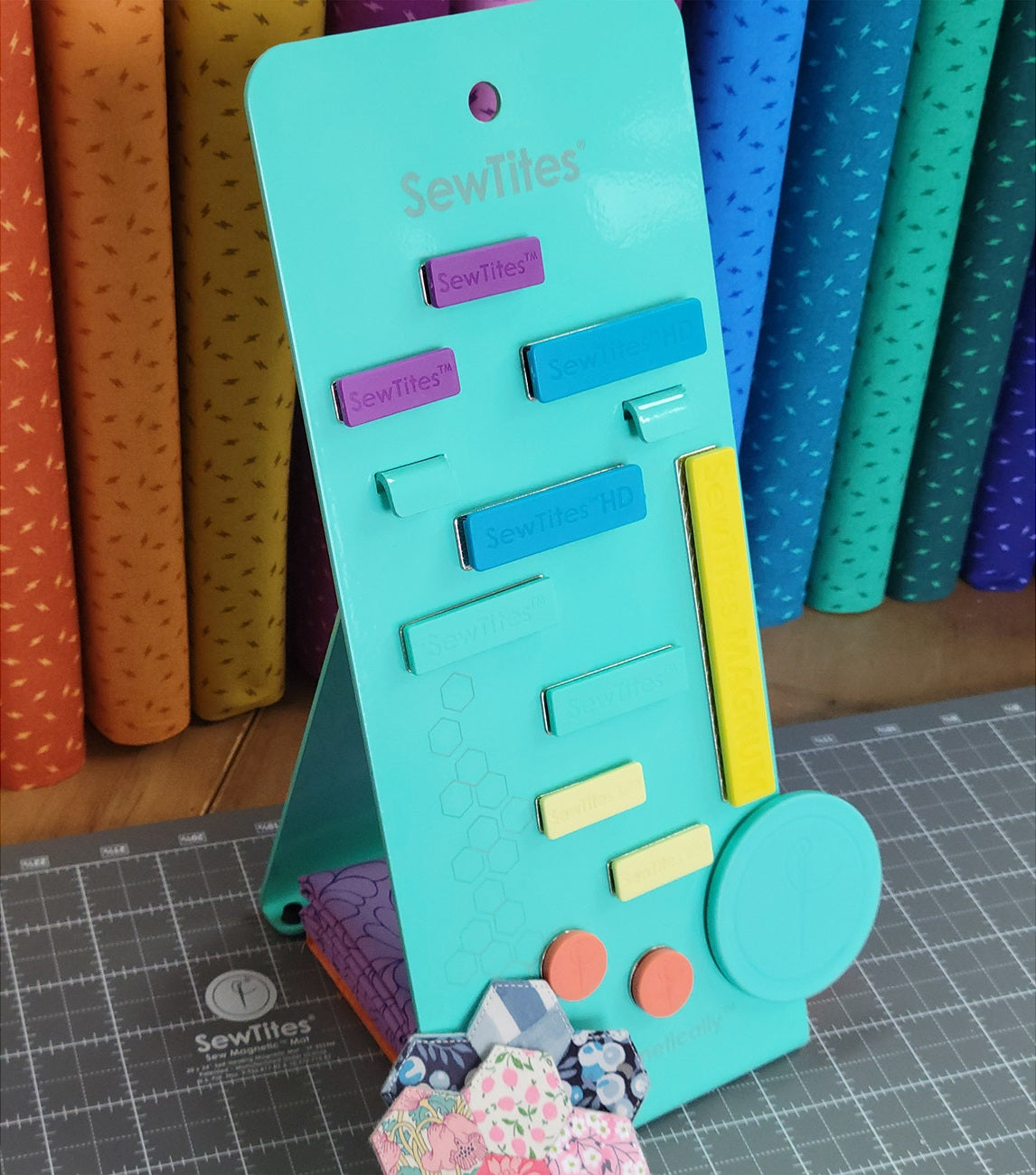 Turquoise sewing tool with colorful components on a cutting mat with fabric in the background