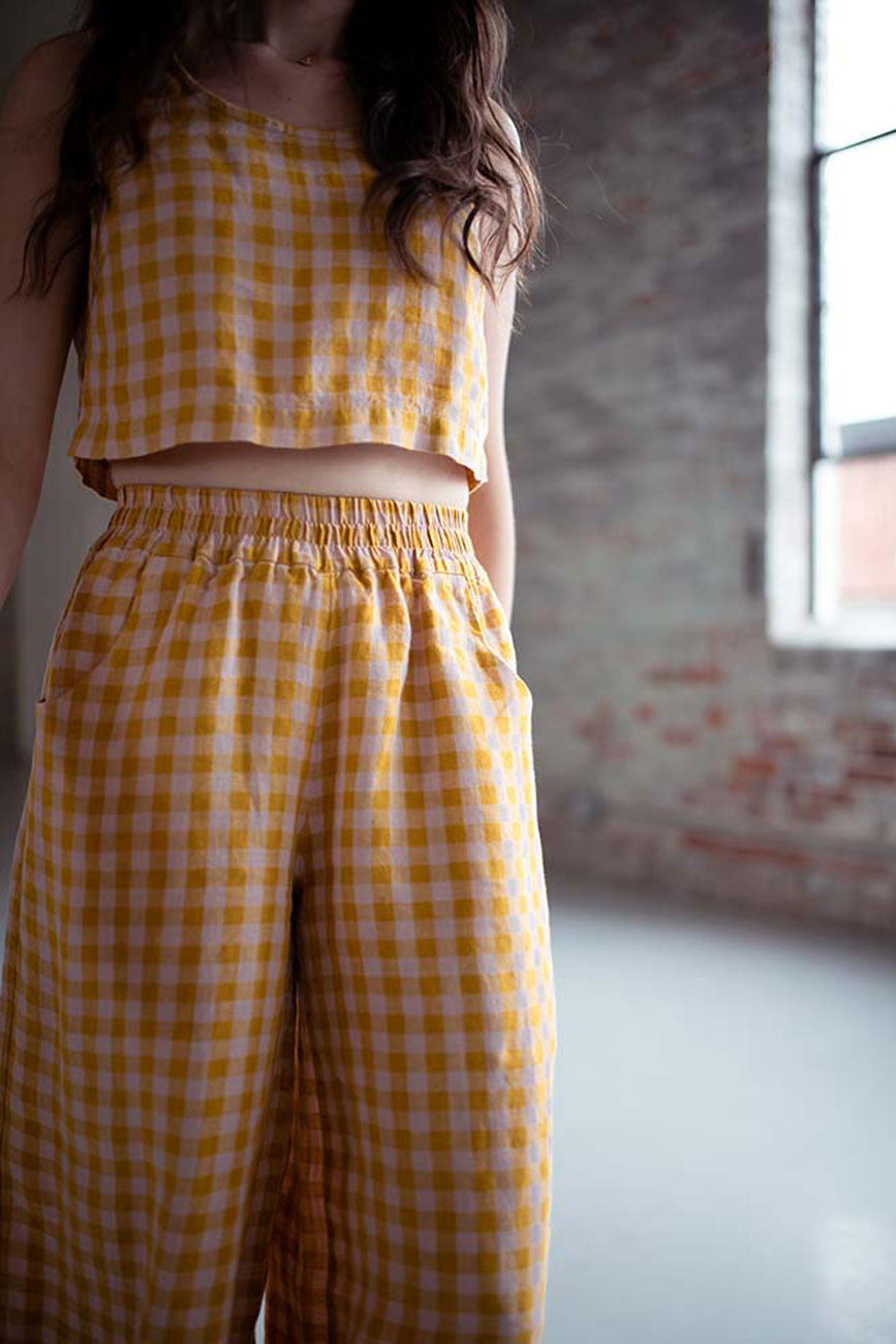Person wearing a yellow gingham outfit in a room with a window and floral rug.